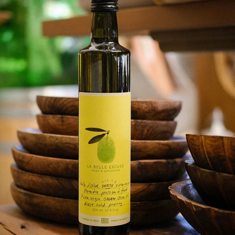 Bottle of olive oil with a yellow label on a wooden surface with bowls in the background
